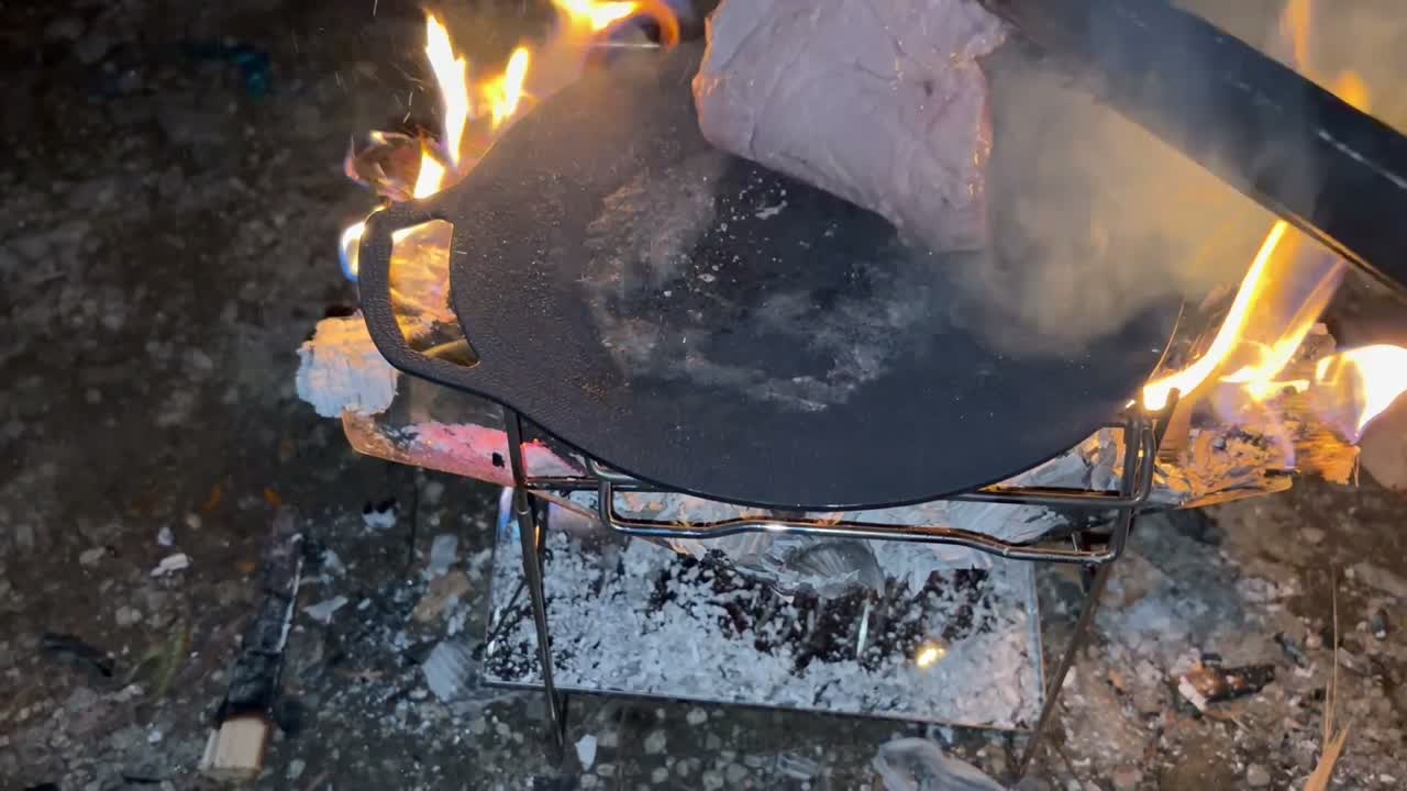 火バサミで肉を返す